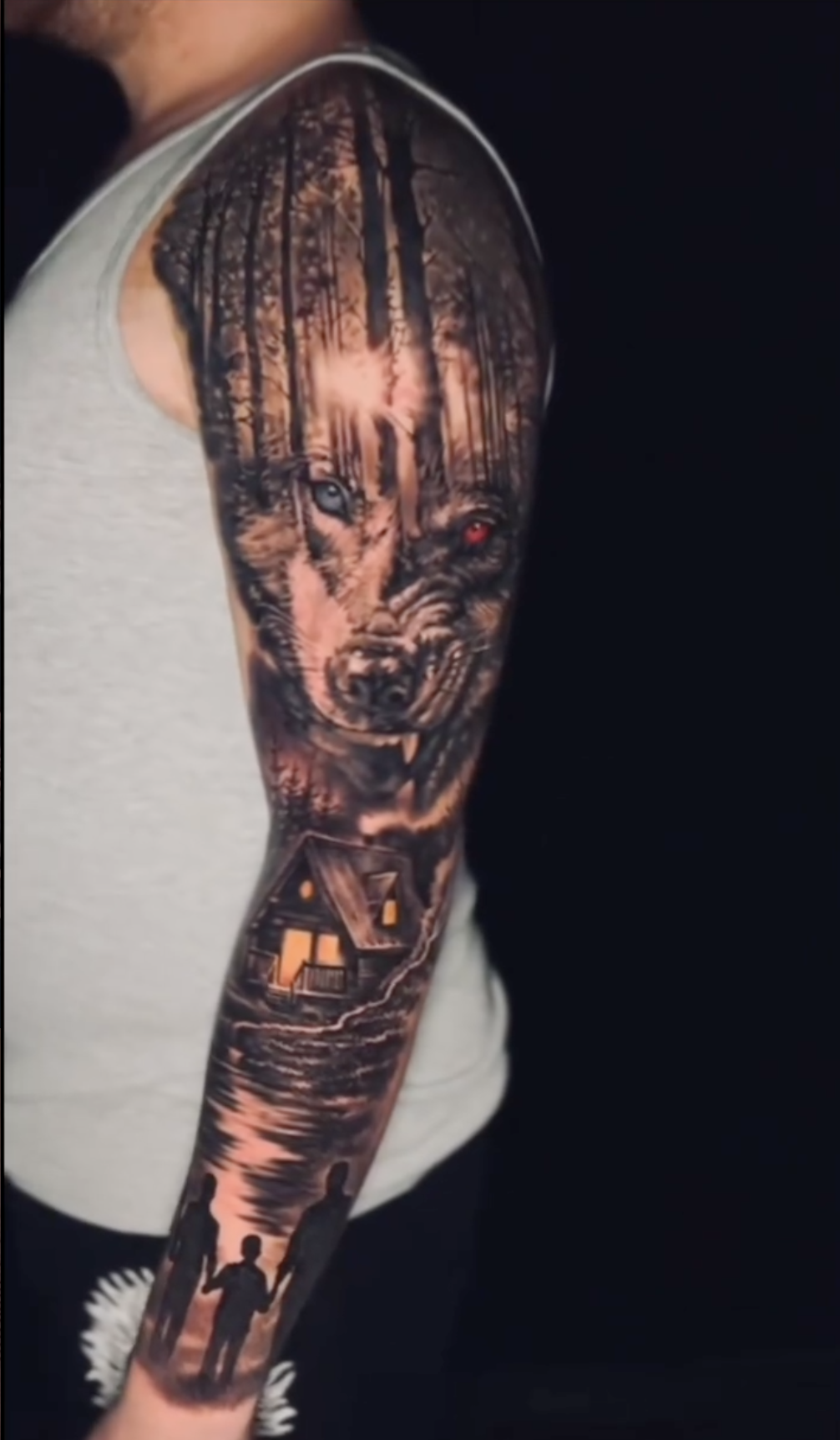 Großes Black and Grey Sleeve Tattoo mit Wolf, Waldhintergrund, Hütte und einer Familie im Vordergrund